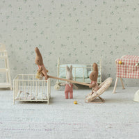 Miniature toys in a play room with toy furniture and toys on a light gray surface.