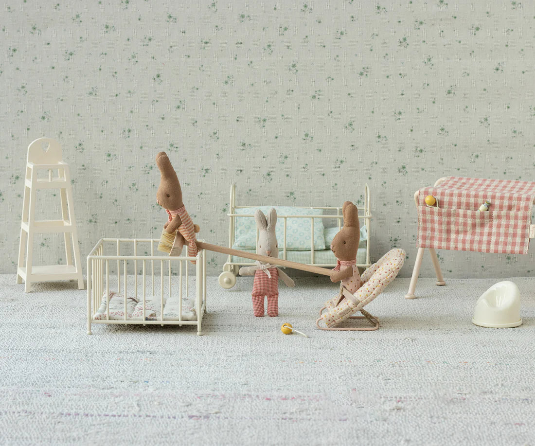 Miniature toys in a play room with toy furniture and toys on a light gray surface.