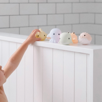 Colorful sea creature-themed shaped bath toys on a white shelf with a tiled wall background.