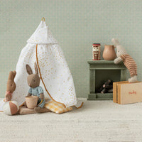 Rabbit children play area with a small tent, stuffed animals, and books against a light green wall.