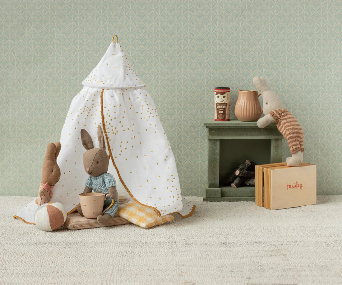 Rabbit children play area with a small tent, stuffed animals, and books against a light green wall.
