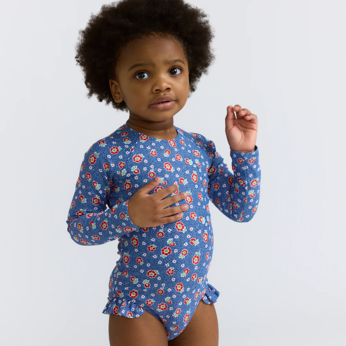 Model wearing a blue floral long-sleeve swimsuit with ruffles at leg opening