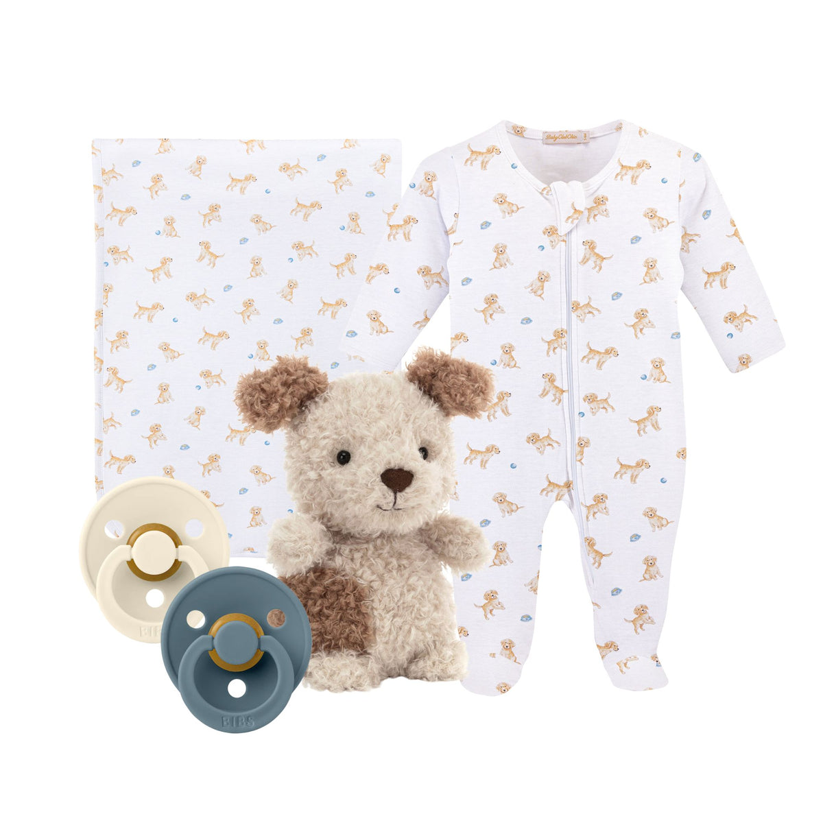 Baby clothing set with dog-themed pajamas, plush toy dog, and two pacifiers on a white background.