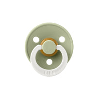 Sage green and white pacifier with a gold center on a white background.