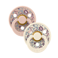 Two white and pink floral-patterned baby pacifiers on a white background.