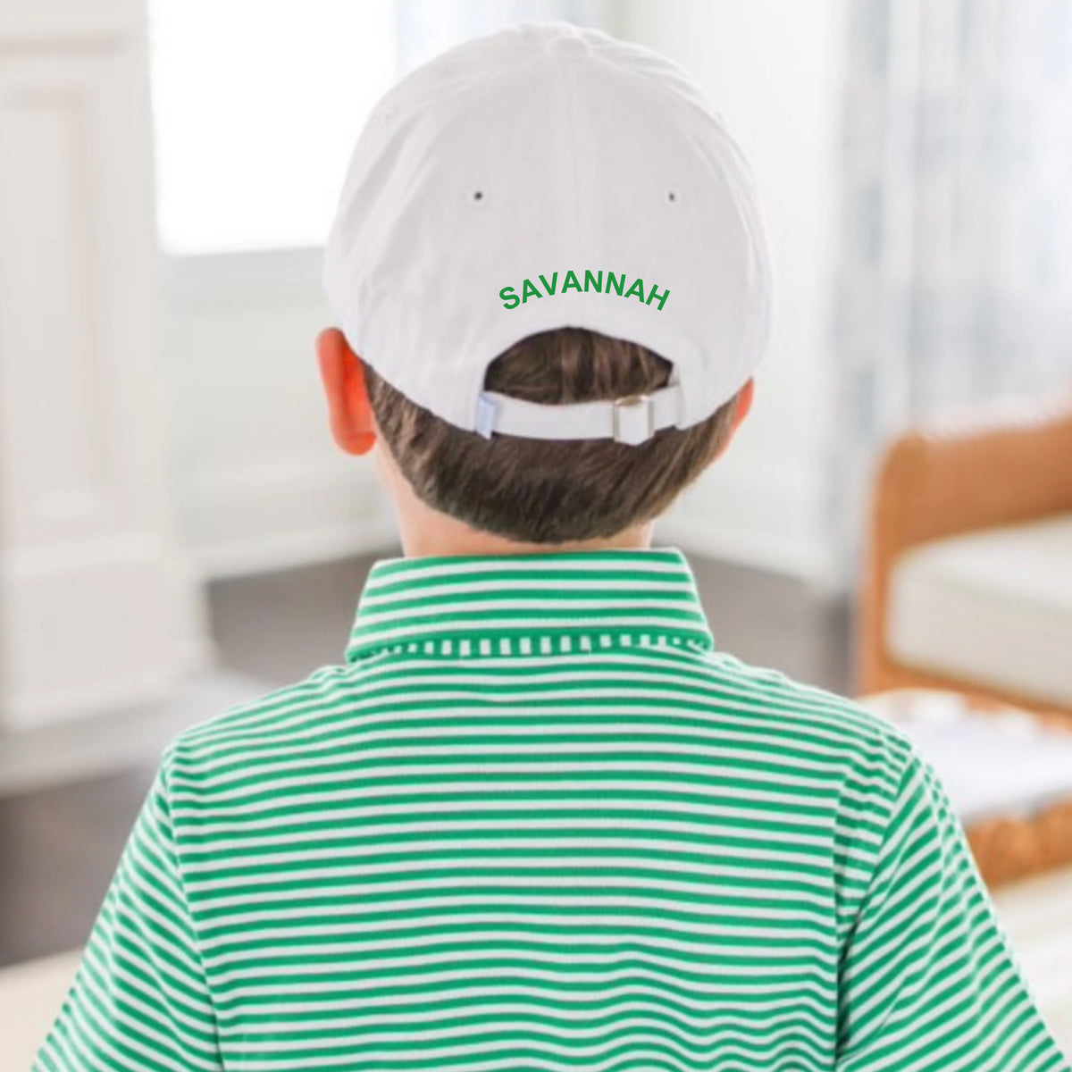 Person wearing a white cap with 'SAVANNAH' on the back, sitting in a room.