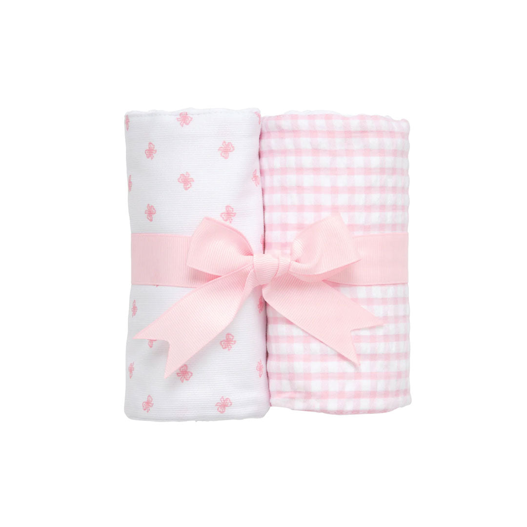 Two rolled burp cloths -pink and white check and pink bow design  - with a pink bow on a white background.