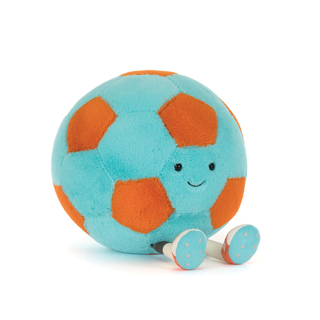 A plush soccer ball toy with a light blue body, orange panels, and a smiling face, sitting on a white background.