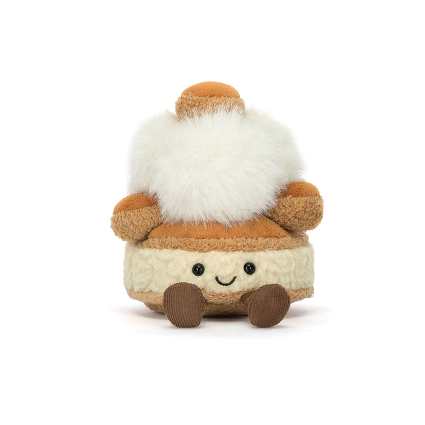 A small plush toy shaped like a cream puff or dessert, with a fluffy white top, tan and cream body, embroidered smiling face, and brown feet, photographed on a clean white background.