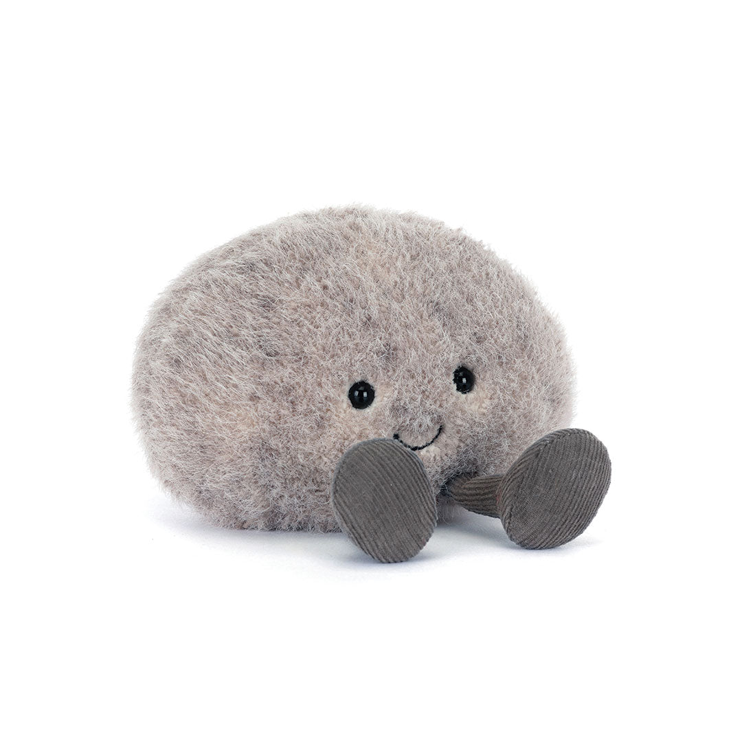 A gray fuzzy plush toy shaped like a rock with small black eyes, a stitched smile, and two gray corduroy feet, photographed on a clean white background.