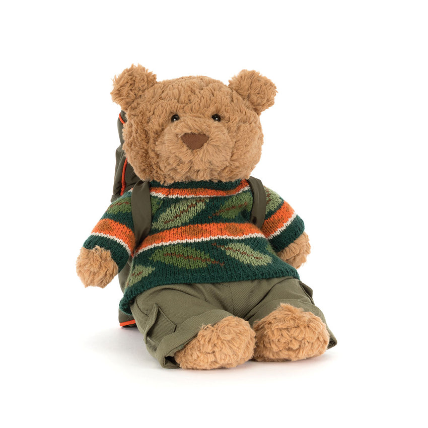 Front view of a  teddy bear wearing a dark striped knit sweater, photographed on a white background.