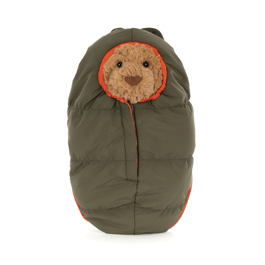 Stuffed bear toy in a green sleeping bag on a white background.