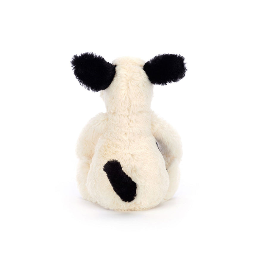 Back of a white and black stuffed animal puppy on a white background.