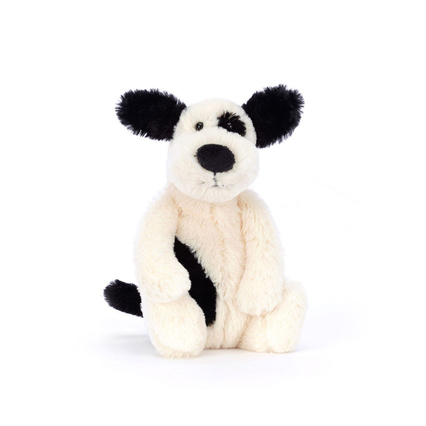 White and black stuffed animal puppy on a white background.