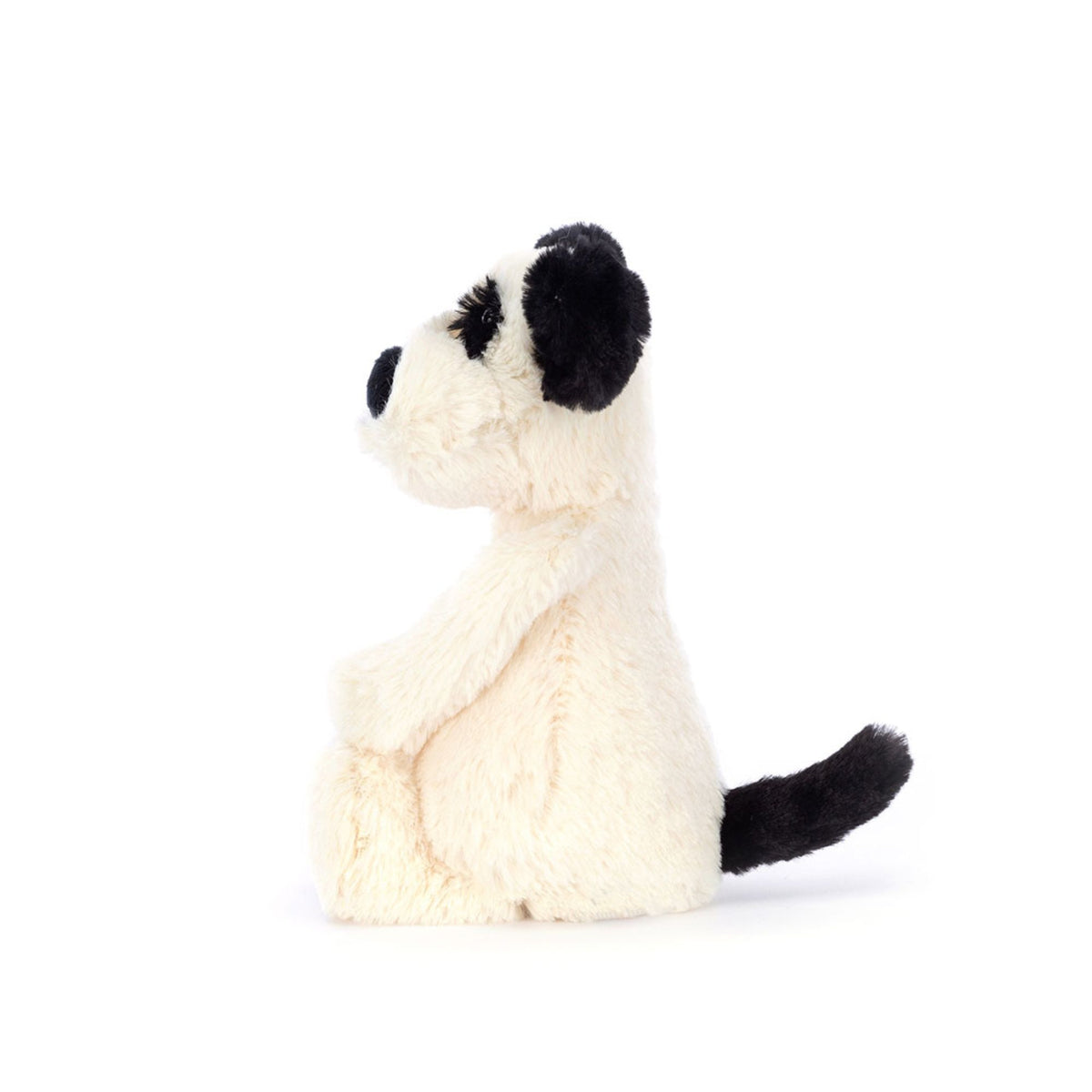 Side of a white and black stuffed animal puppy on a white background.