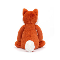 A plush fox toy shown from the back, featuring orange-brown fur with white accents on its inner ears, chin, and tail, set against a plain white background.