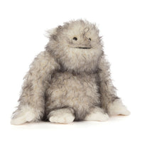 A fluffy gray and white furry "yeti" critter plush toy with small black eyes and a stitched smile, sitting against a plain white background.
