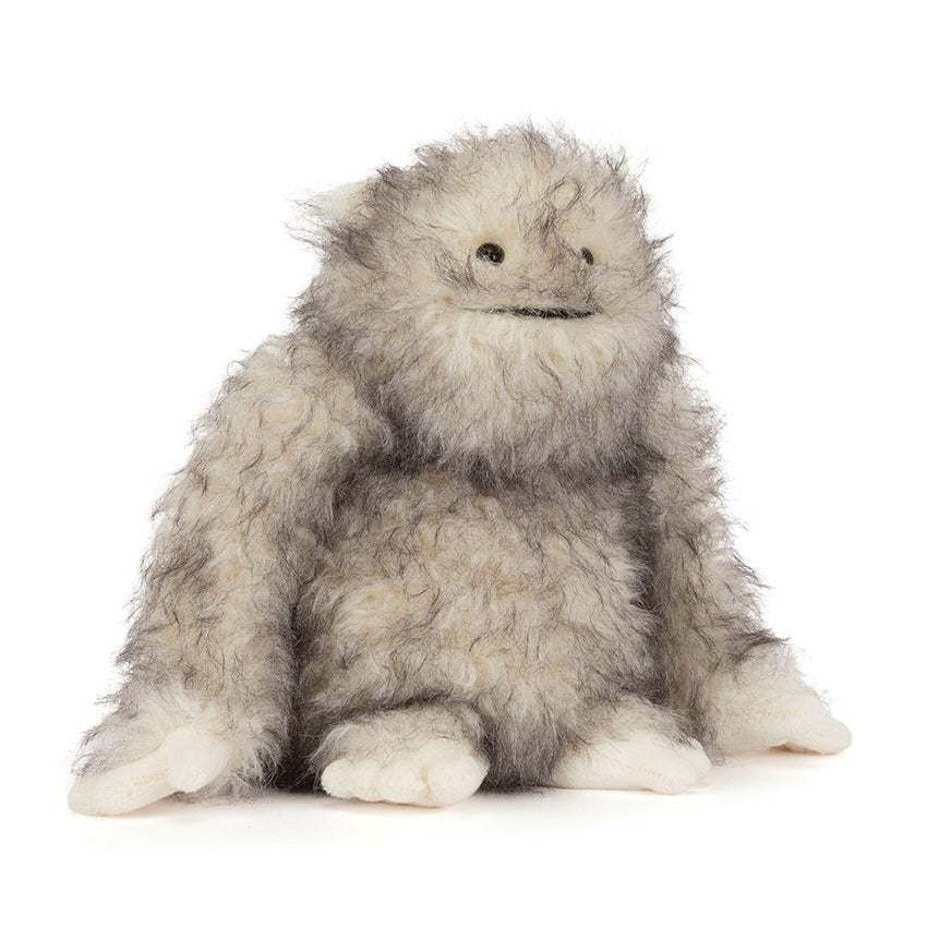 A fluffy gray and white furry "yeti" critter plush toy with small black eyes and a stitched smile, sitting against a plain white background.