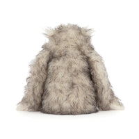 Back view of a fluffy gray and white furry "yeti" critter plush toy sitting against a plain white background.
