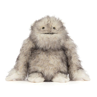 A fluffy gray and white furry "yeti" critter plush toy with small black eyes and a stitched smile, sitting against a plain white background.
