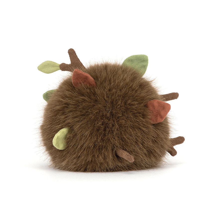 Back view of a stuffed round toy that is a bunch of dirt, leaves and twigs shown on a white background.