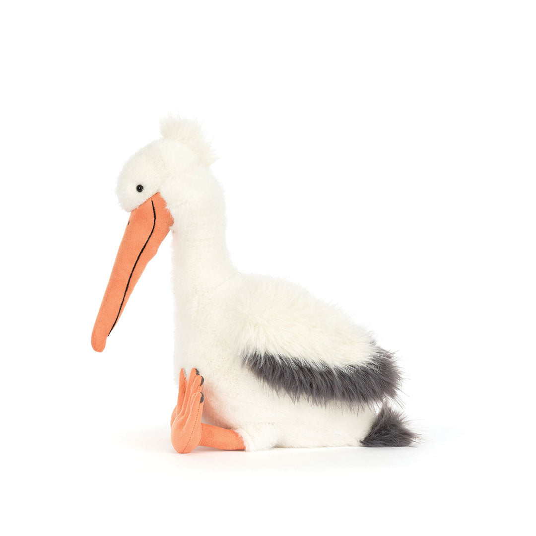 A plush stuffed pelican toy sitting on a plain white background. The toy has white fur, a long orange beak, orange legs, and a dark gray back and tail.