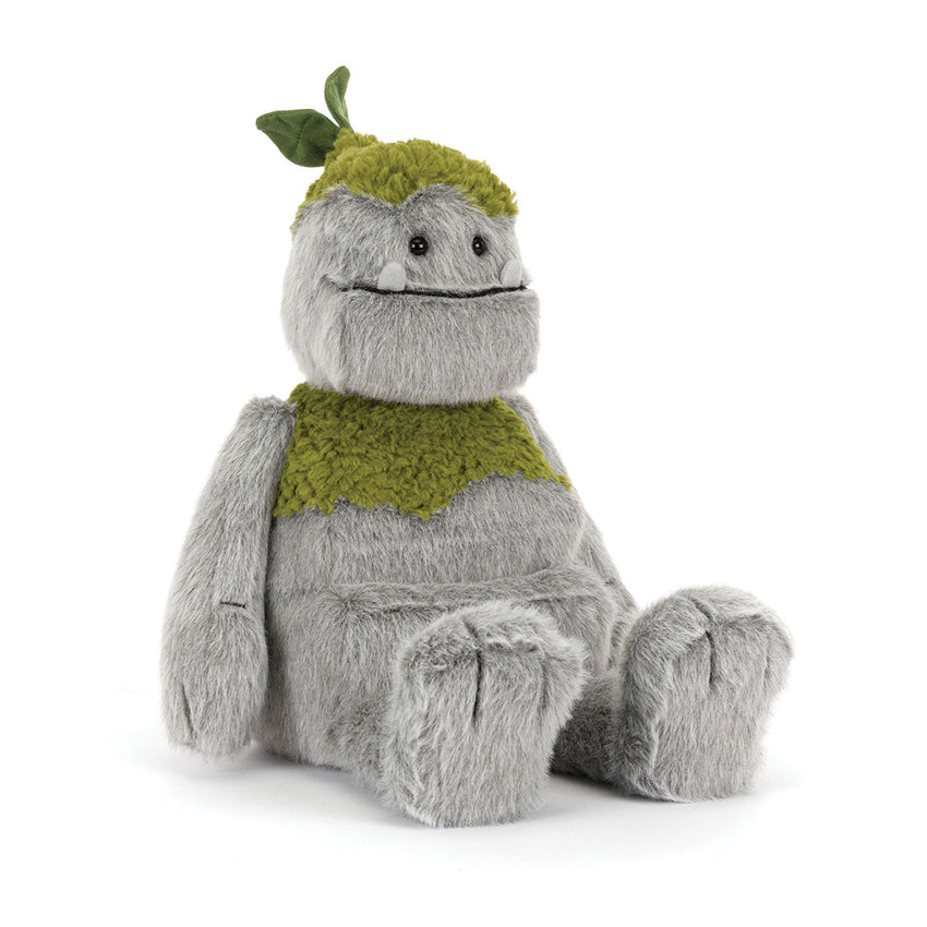 A plush toy figure with soft gray fur sitting in profile, wearing a textured olive-green knit hat with a leaf detail and a matching green knit scarf, photographed on a white background.