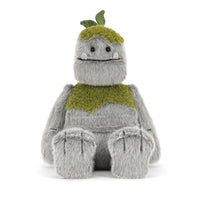 A plush toy character with a fuzzy gray body, olive green textured chest and headpiece with small green leaves, sitting against a plain white background.