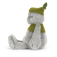 A plush toy figure with soft gray fur sitting in profile, wearing a textured olive-green knit hat with a leaf detail and a matching green knit scarf, photographed on a white background.