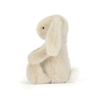 A cream-colored plush bunny toy sitting on a seamless white background.