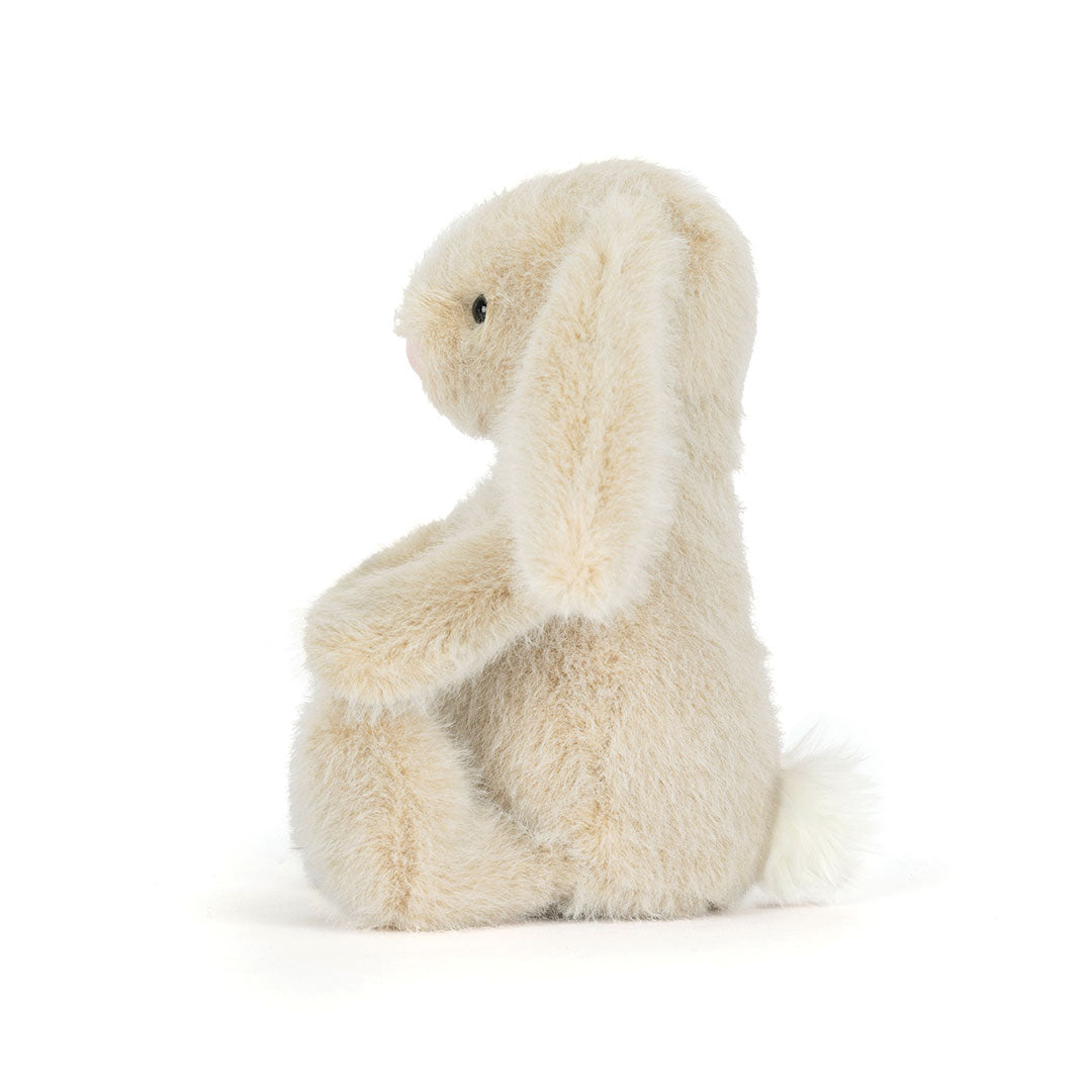 A cream-colored plush bunny toy sitting on a seamless white background.