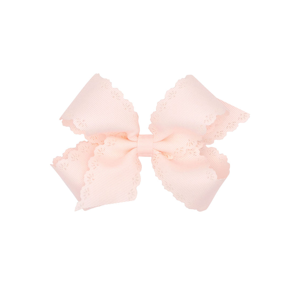 Rose colored bow with scalloped edges on a white background.
