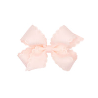 Rose colored bow with scalloped edges on a white background.
