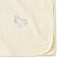 Close-up of a folded yellow receiving  blanket with giraffes embroidery on a white background.