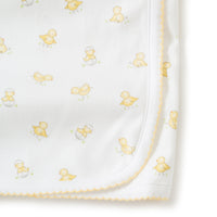 Close up of white baby receiving blanket with  yellow duck patterns on a white background.