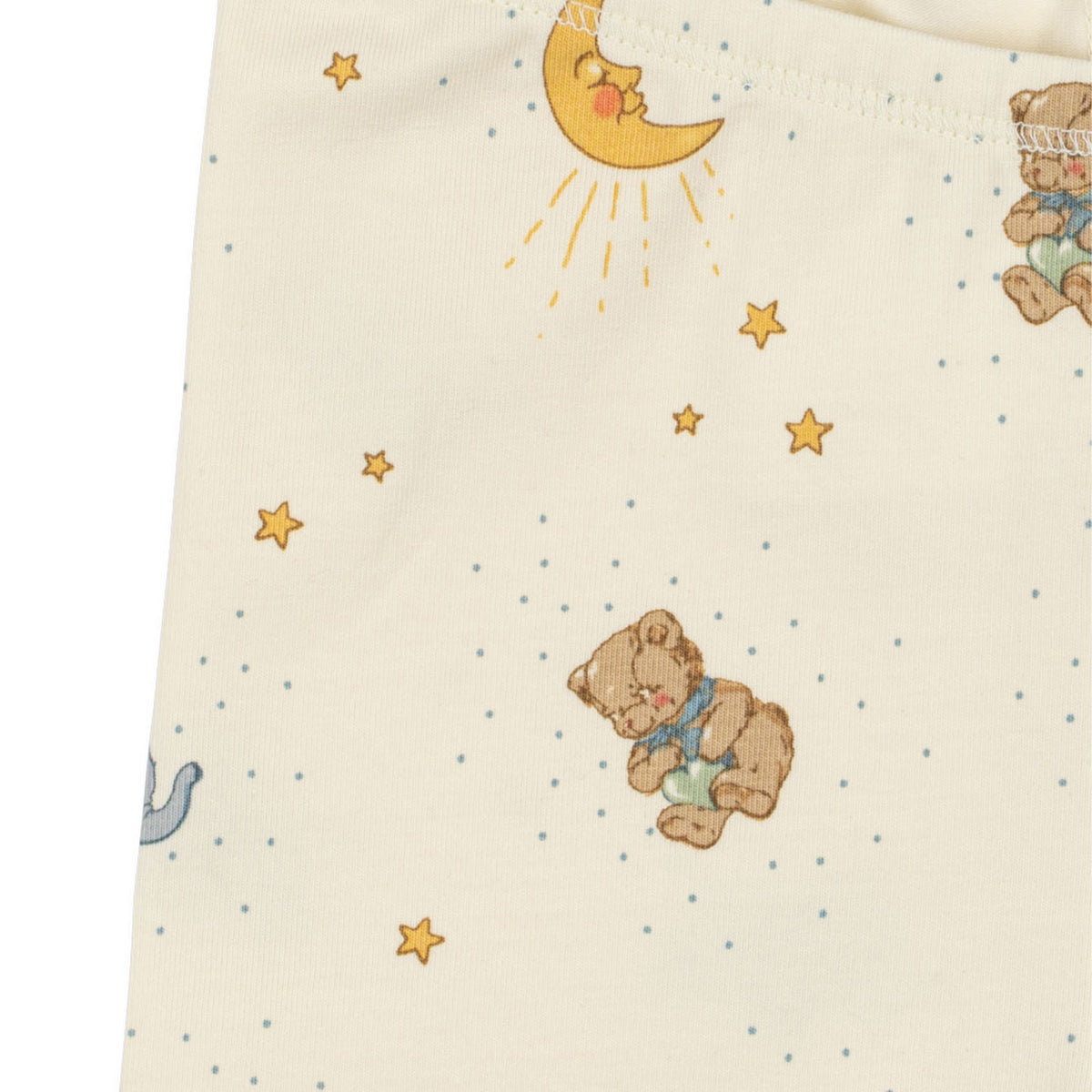 Close-up of a cream-colored baby pants with a printed pattern of teddy bears, a yellow crescent moon, stars, and small blue dots.