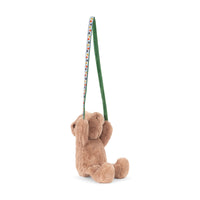 Brown teddy bear with a fabric tie in both front paws shown on a white background.