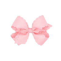 Pink bow with scalloped edges on white background.