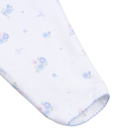 Close-up of a baby sleeve featuring a delicate pastel floral print with blue and pink flowers and green leaves, finished with a light blue scalloped edge.