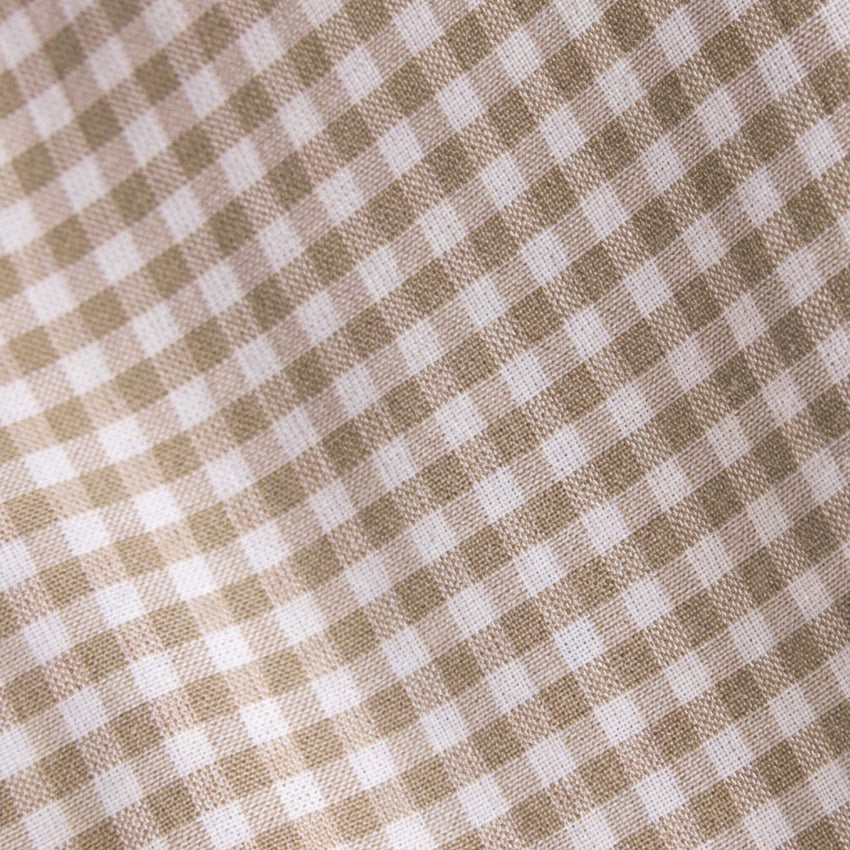 A close-up of a woven fabric with a small gingham check pattern in warm beige and white.