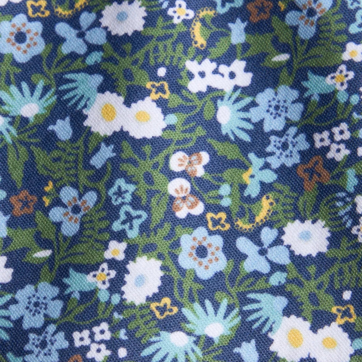 A close-up of a woven fabric with a dense floral pattern featuring light blue, white, and green flowers on a dark navy blue background.