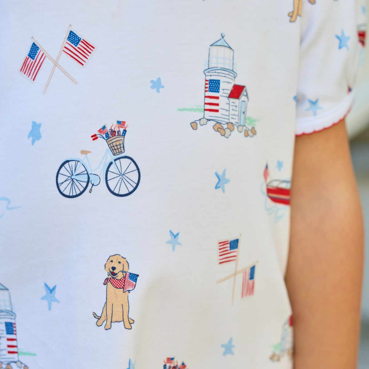 Close up of print of dress fabric featuring flags, bikes, boats and buildings in an outdoor setting. 