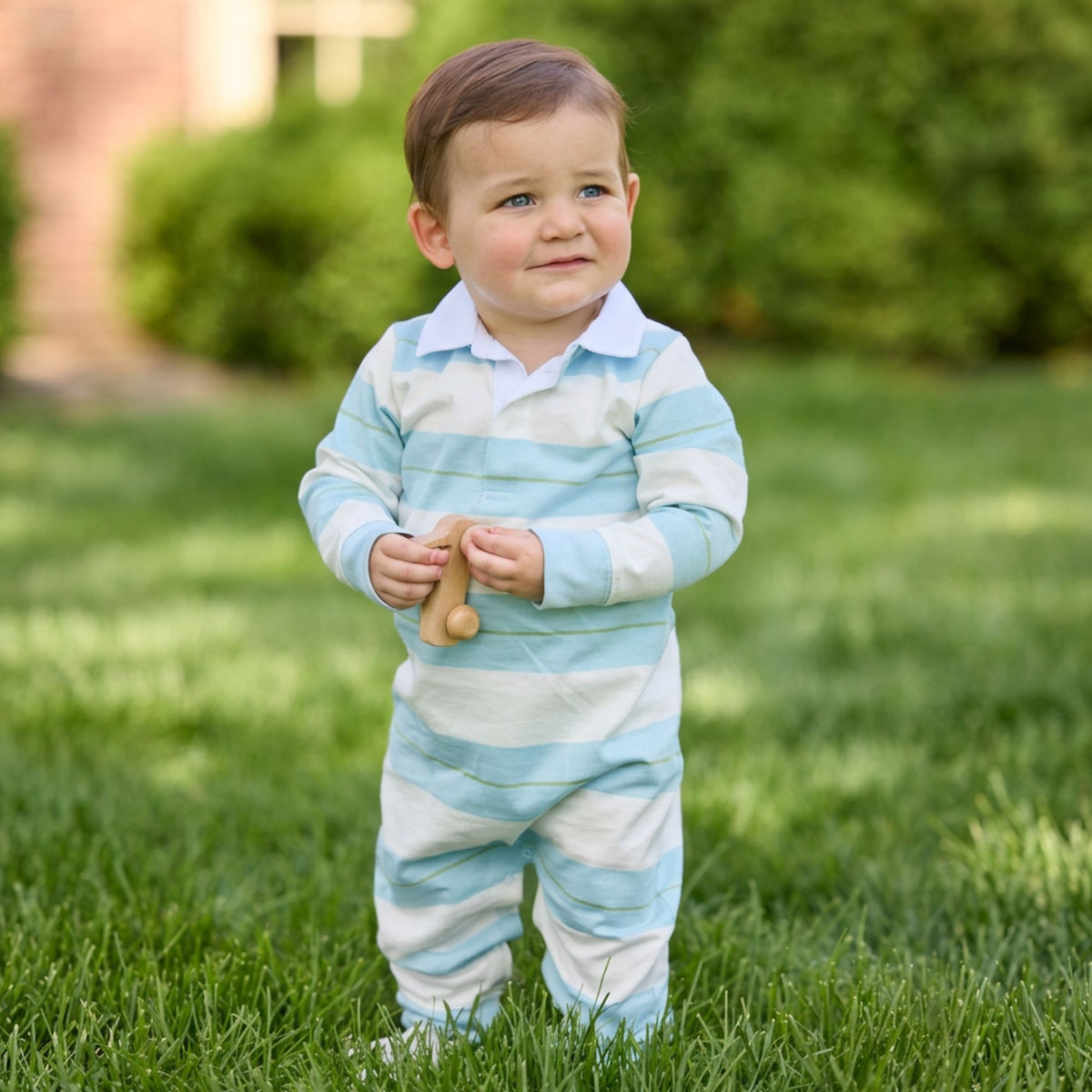 Young child wearing rugby polo romper with wide blue and white stripes.