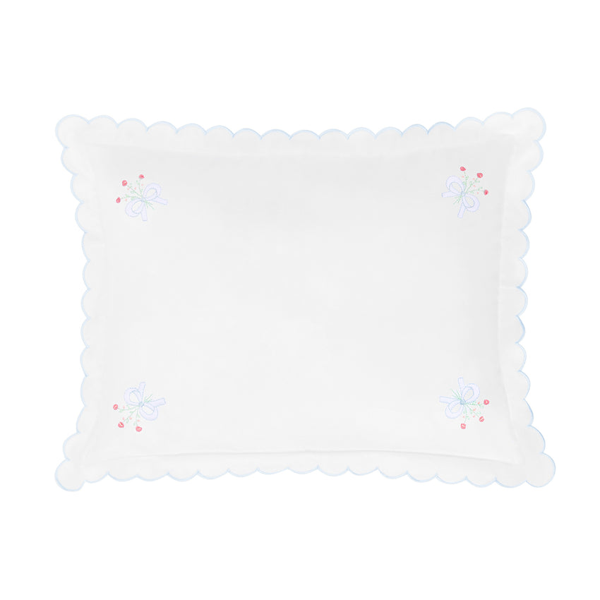 White decorative pillow with scalloped edge and embroidered details on a white background.