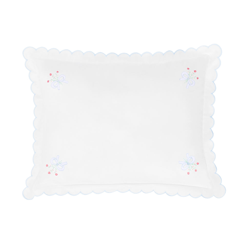 White decorative pillow with scalloped edge and embroidered details on a white background.