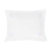 White decorative pillow with scalloped edge and embroidered details on a white background.