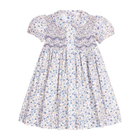 Blue themed floral dress with ruffled puff sleeves and embroidery on bodice on a white background.