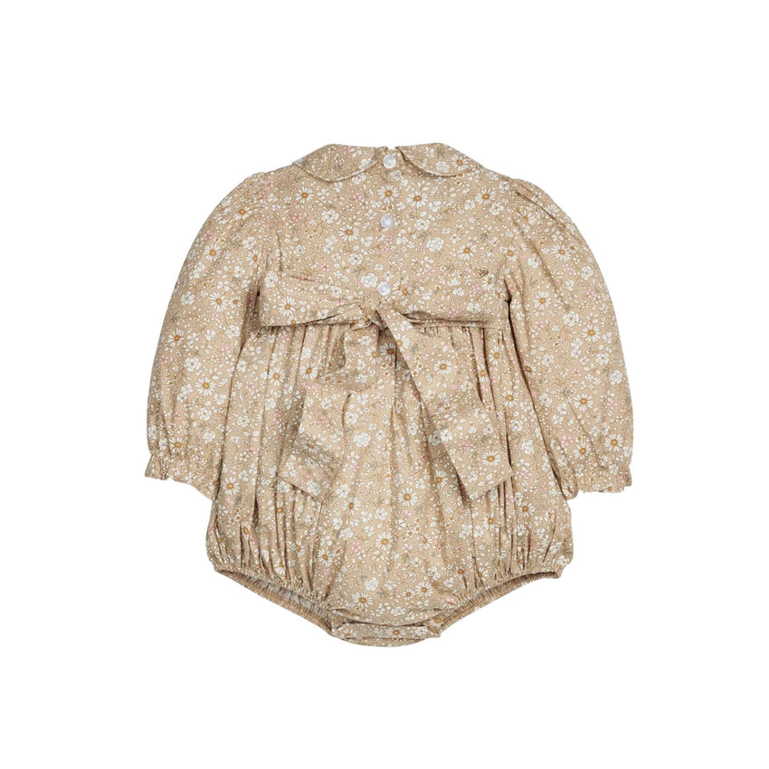 Back view of a baby romper in a beige and white daisy floral print, featuring long puff sleeves, a Peter Pan collar, and a large bow detail at the bodice shown on a white background.