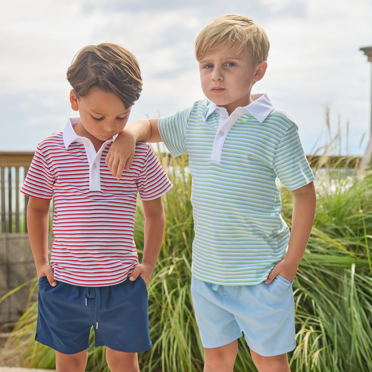 Two boys outside wearing striped t-shirts and shorts.