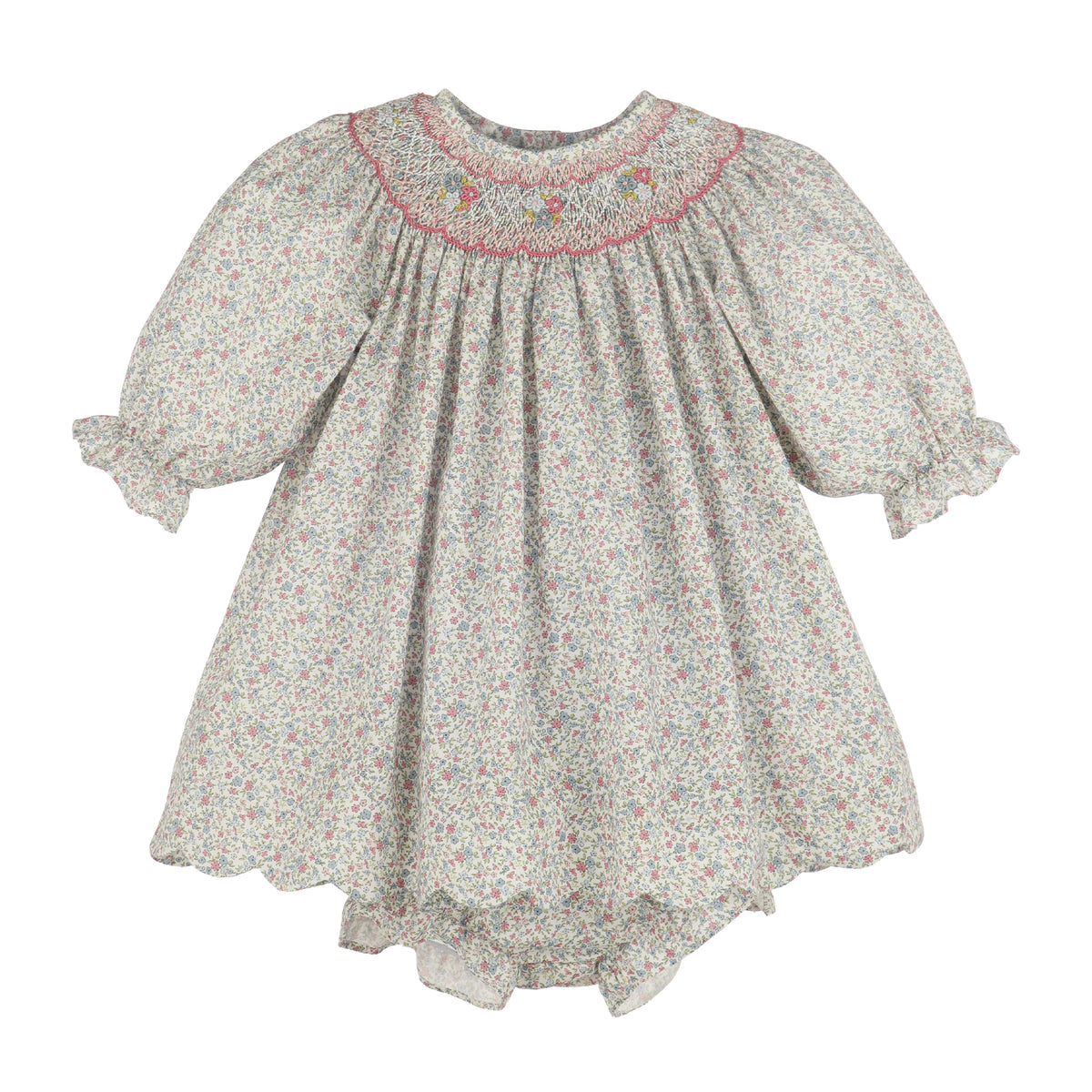 A girl's smocked dress featuring a delicate multicolor floral print on a light grayish-beige background, with a pink embroidered neckline and ruffled sleeves.